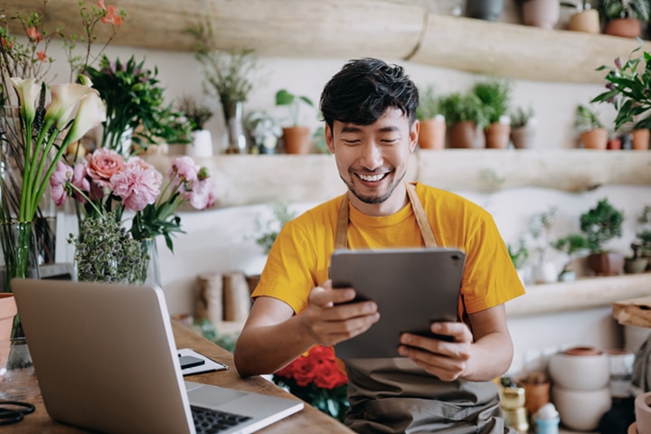 A plant shop owner smiling and looking at a tablet