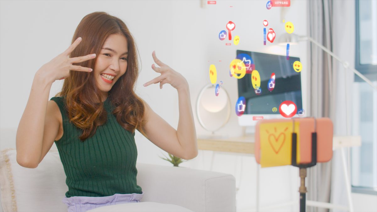 A woman smiling and signing to her phone, which is placed on a stand