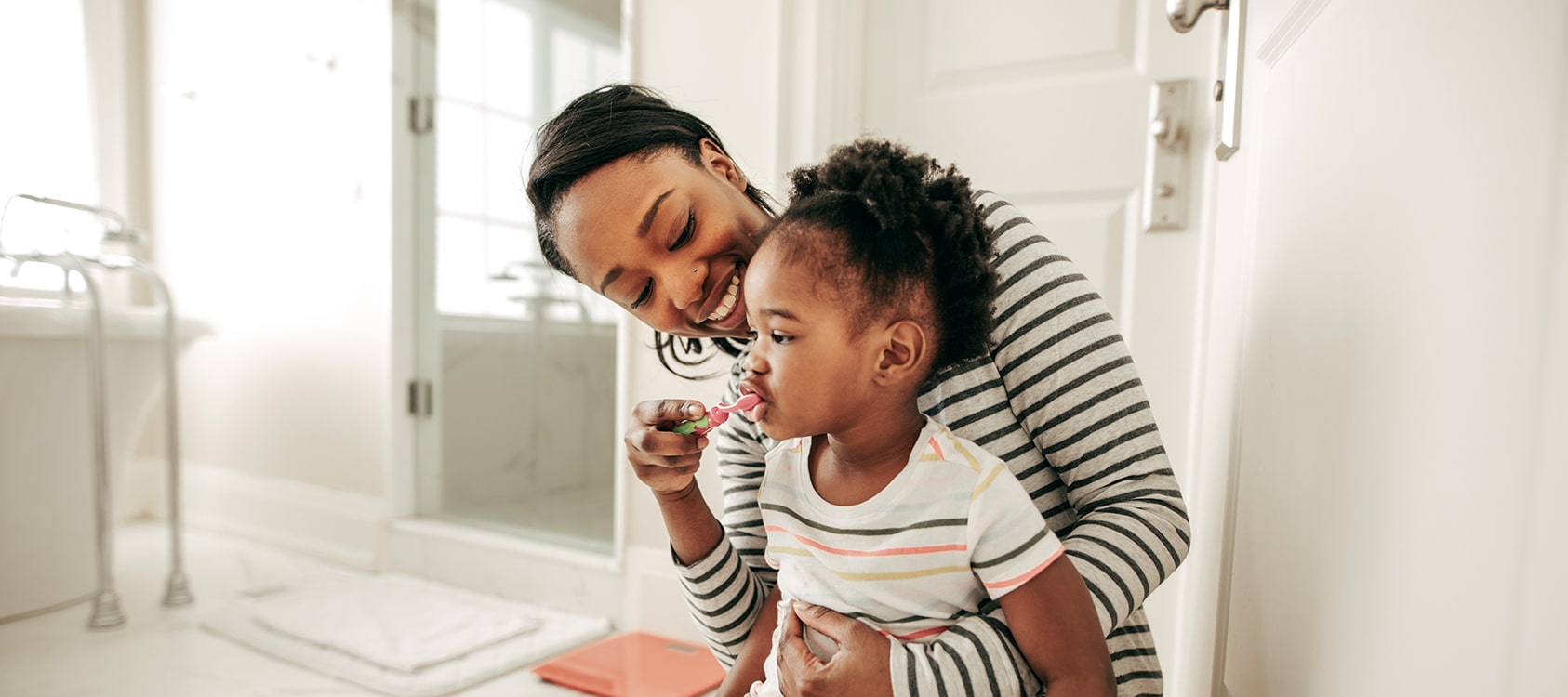 A mother brushing her daughter's teeth