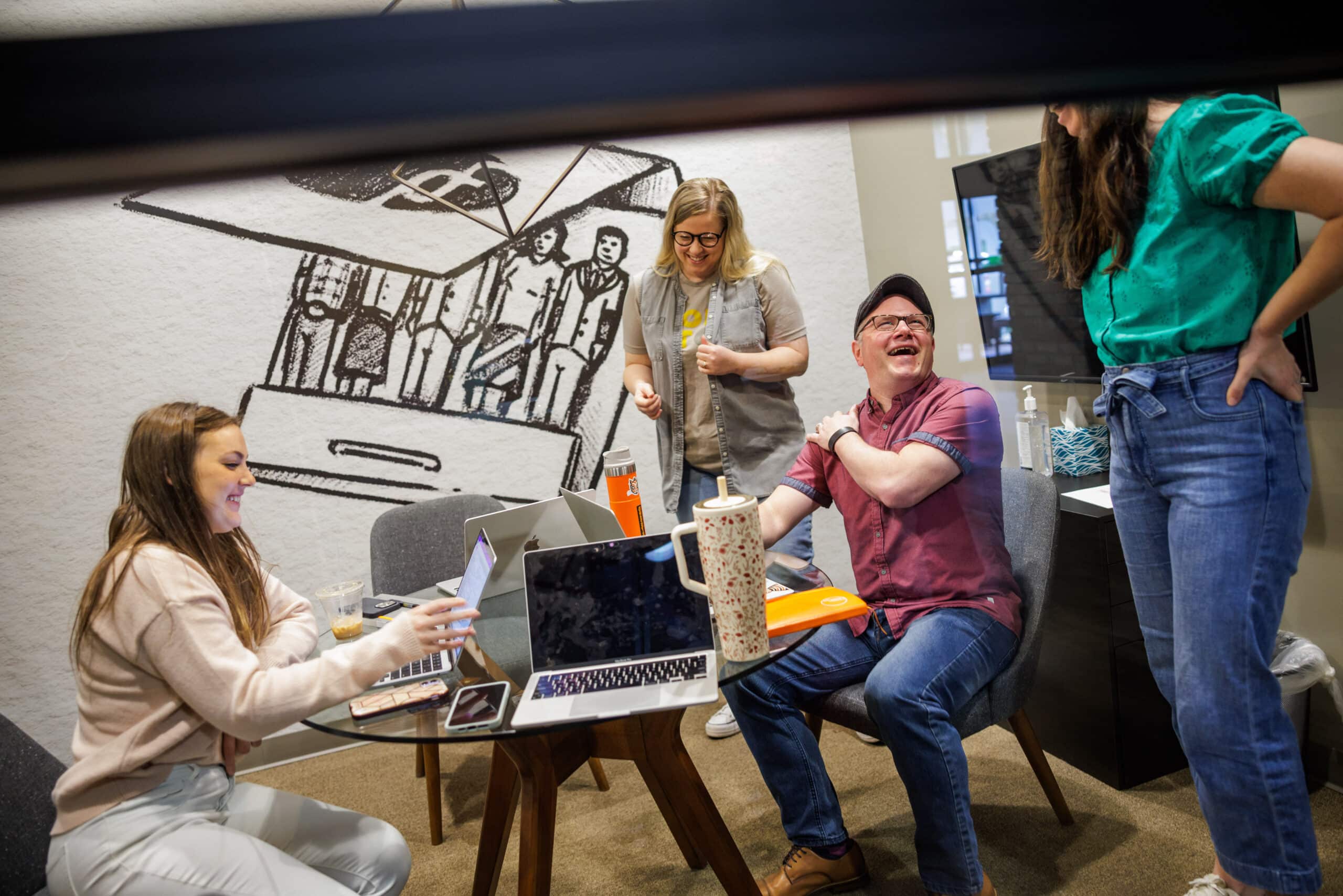 A conference room with four Pathfinders laughing